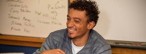 An FLCC student sitting in front of a whiteboard covered in notes.