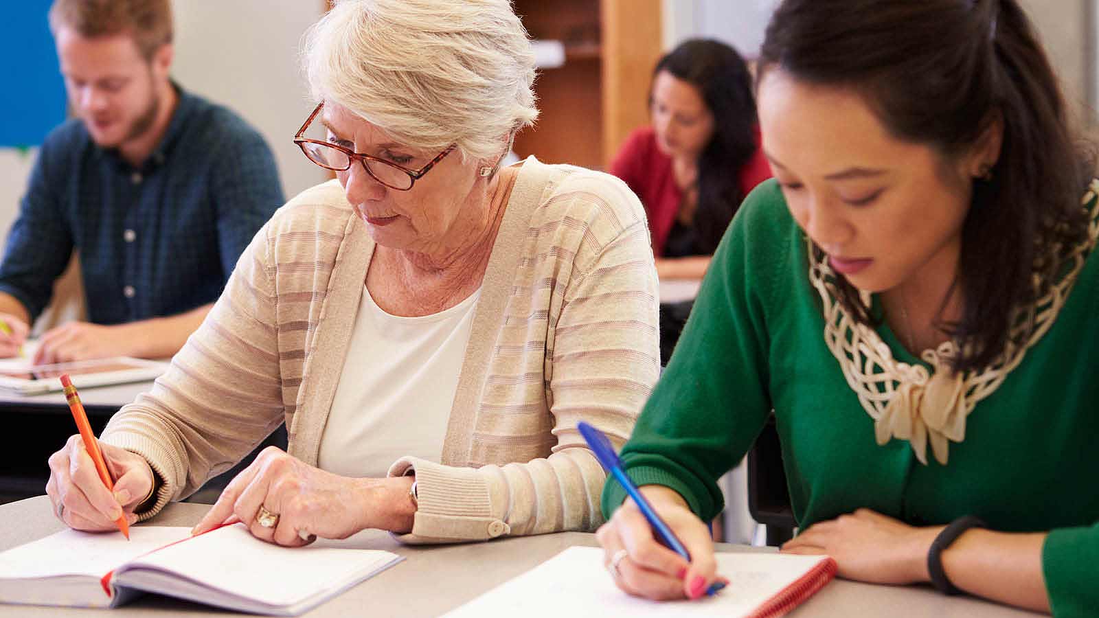 Students writing and taking notes in a classroom setting