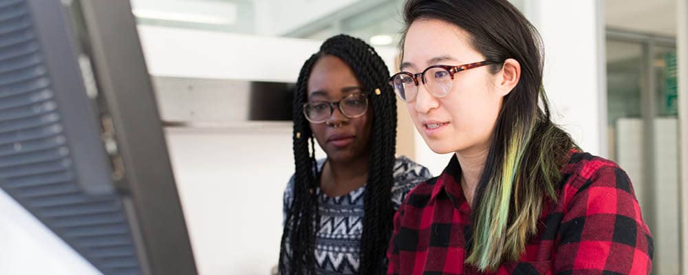 Two students reviewing information on a computer screen.