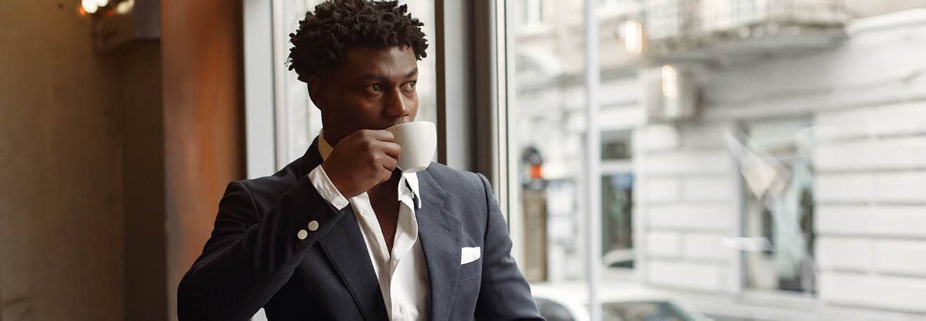 A person in business casual attire sips coffee in the lounge of a downtown hotel.