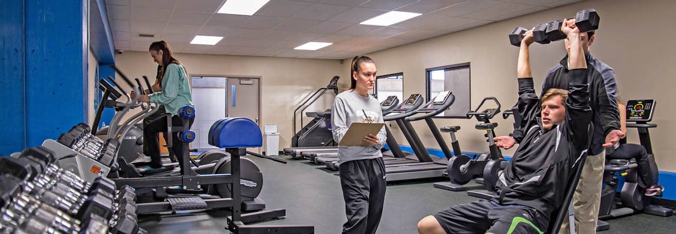 Kinesiology and Human Performance students in athletic training room evaluating a fitness routine.